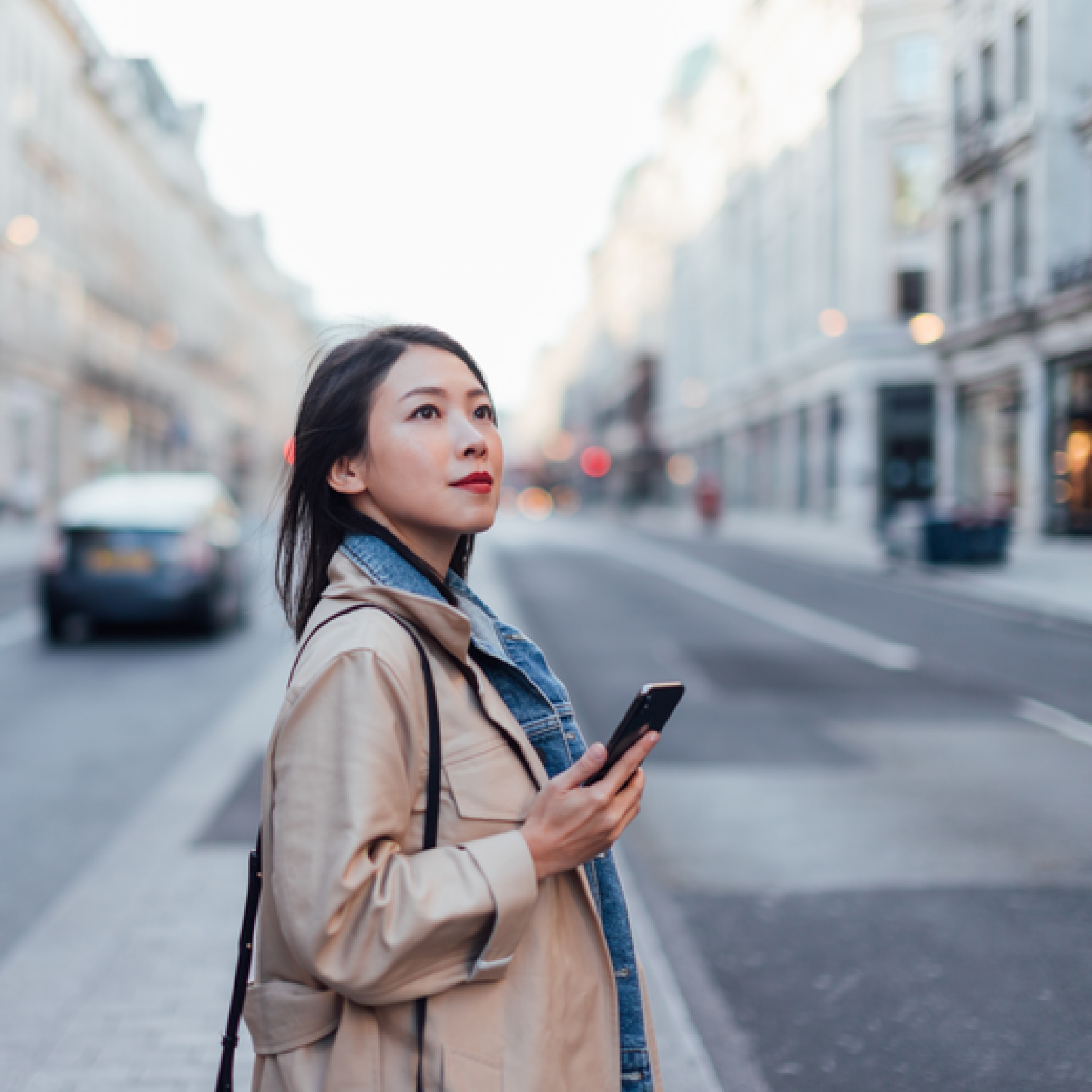 Woman walking across street while looking at her Capital One app on her phone