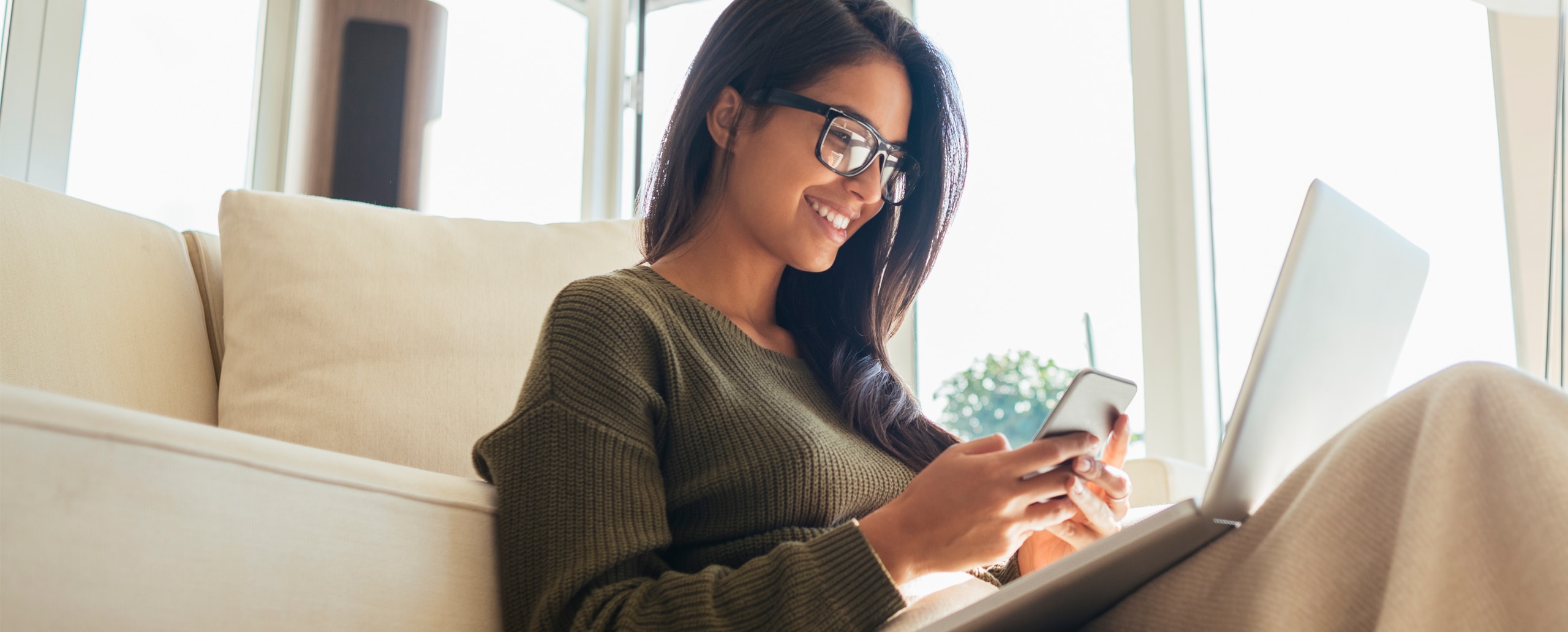A woman sitting on a couch with her computer