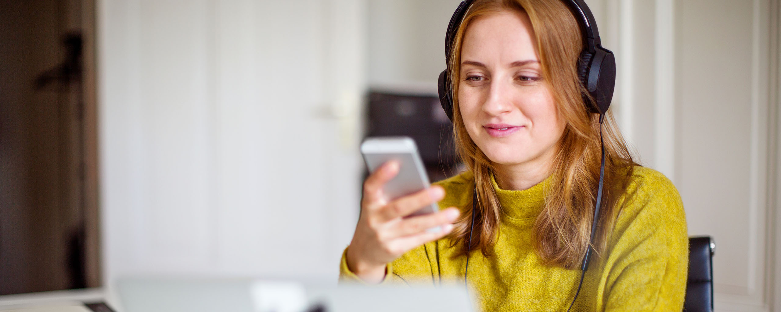 A woman in headphones locks her credit card on her mobile device.