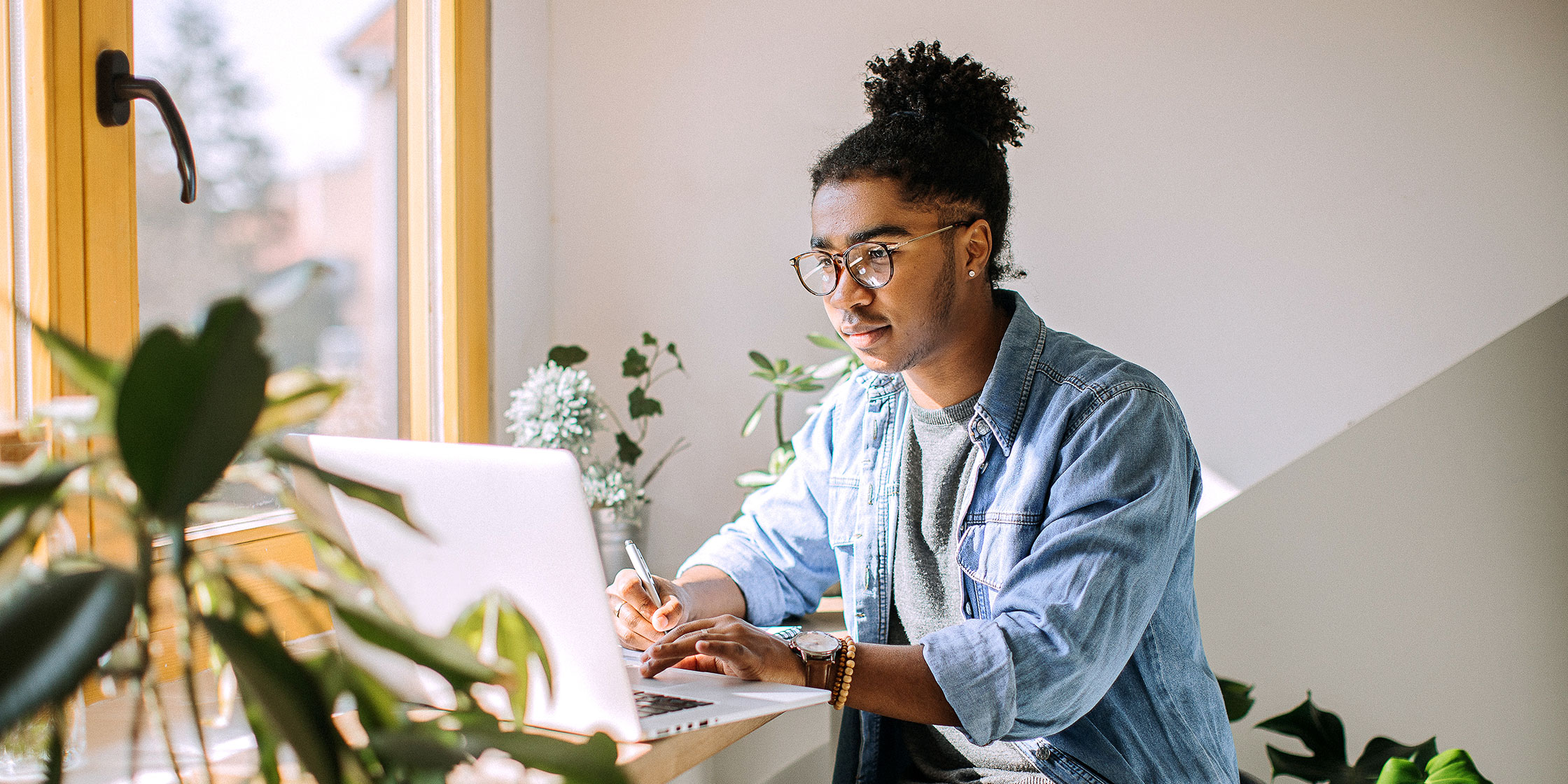 A person sits in front of their laptop and takes notes on the differences between principal and interest.