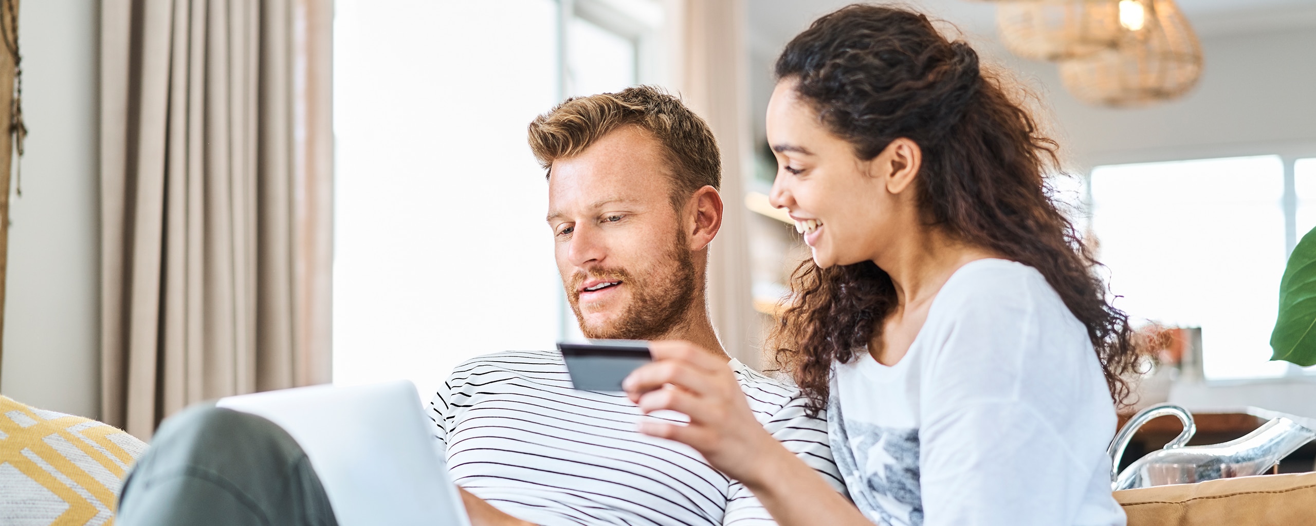 Couple using a laptop to shop online with a credit card.