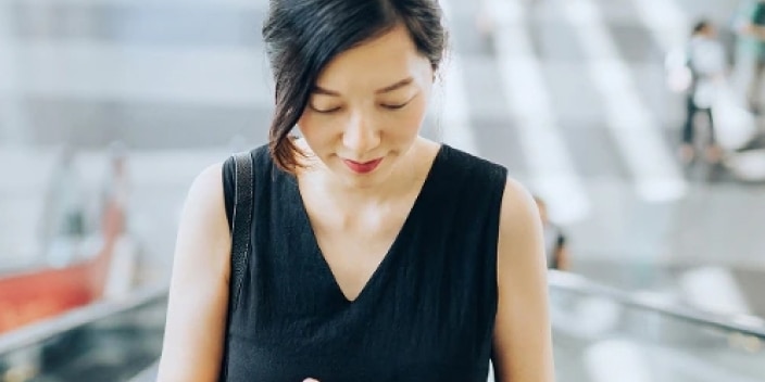 Woman looking at her phone to educate herself on scams