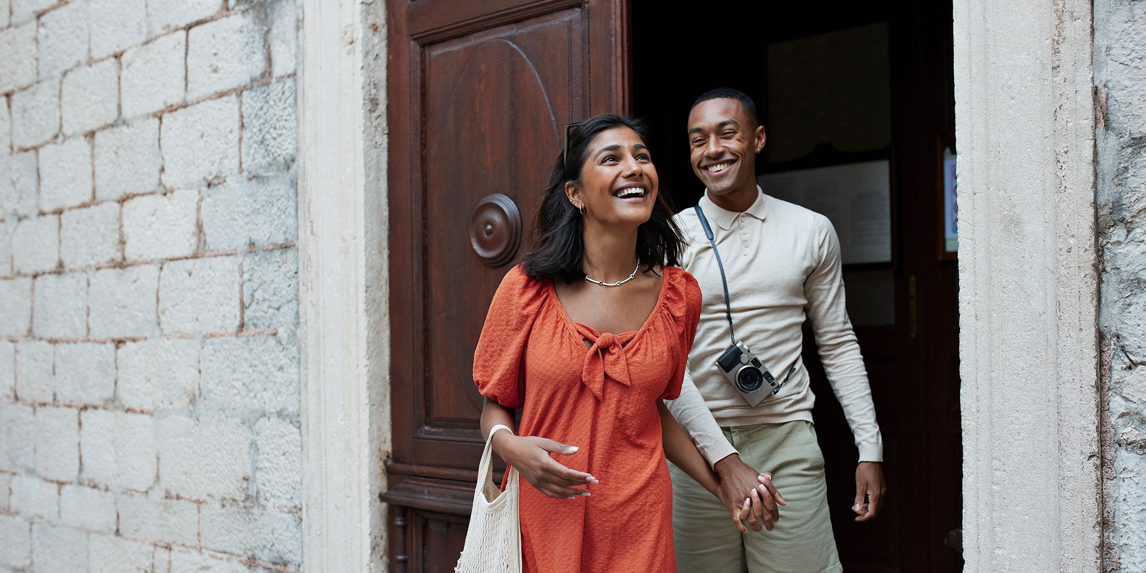 A couple exits a building while enjoying a vacation.