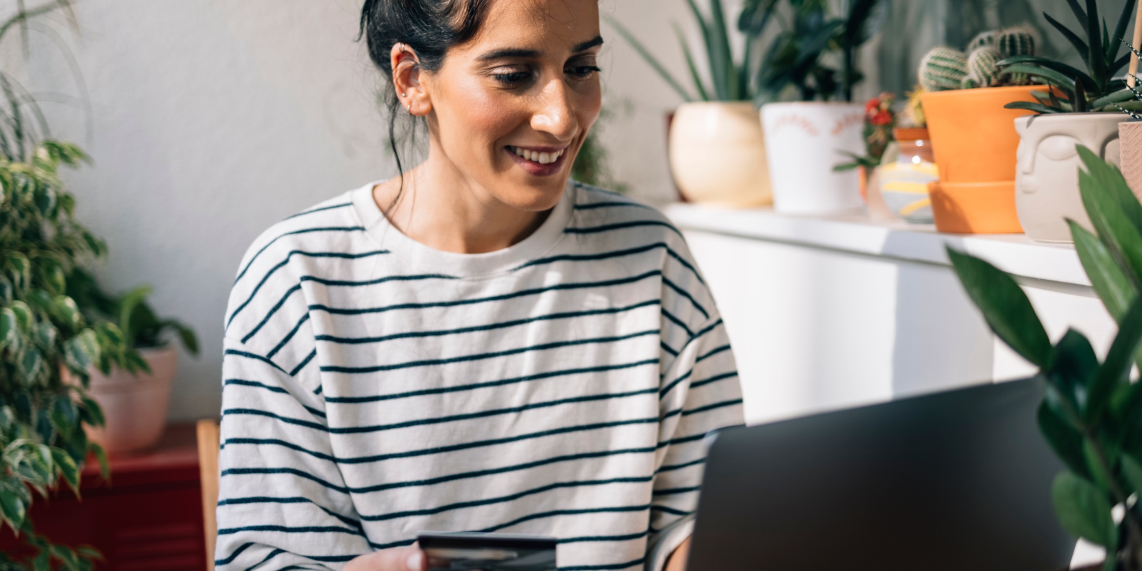 A woman is holding a credit card while inputting details into a laptop.