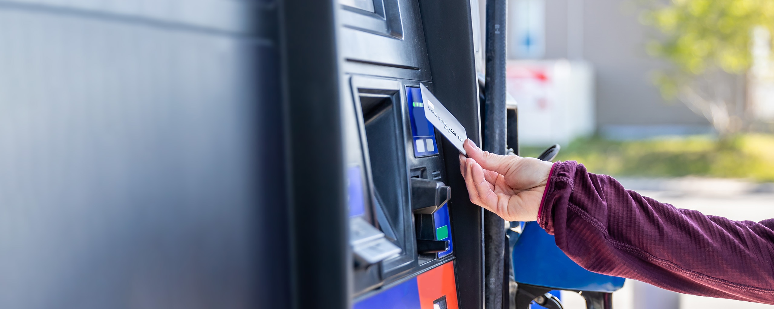 A woman uses her contactless card to pay for gas at the pump.